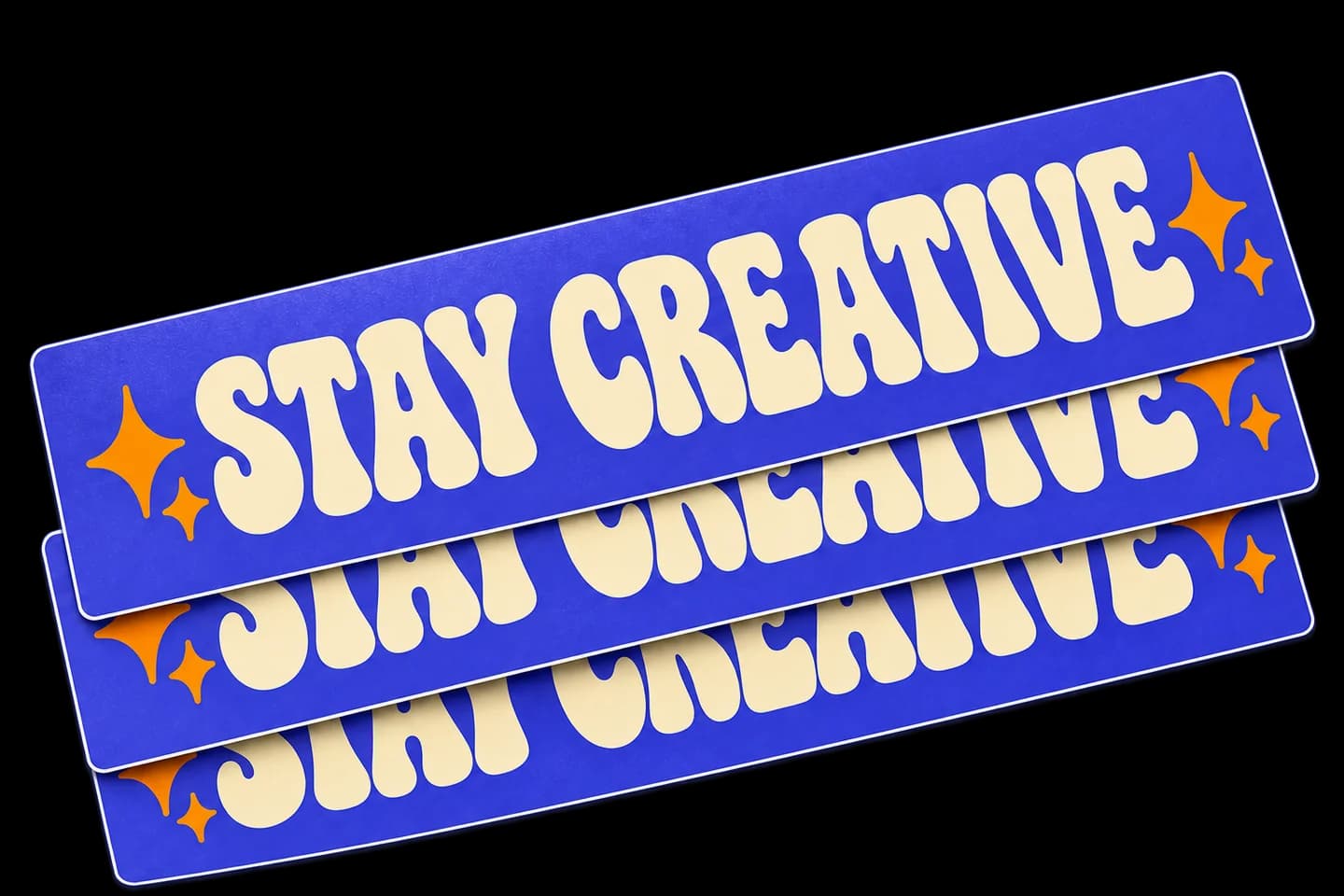 Stack of purple rectangular Stay Creative stickers with cream lettering and orange stars