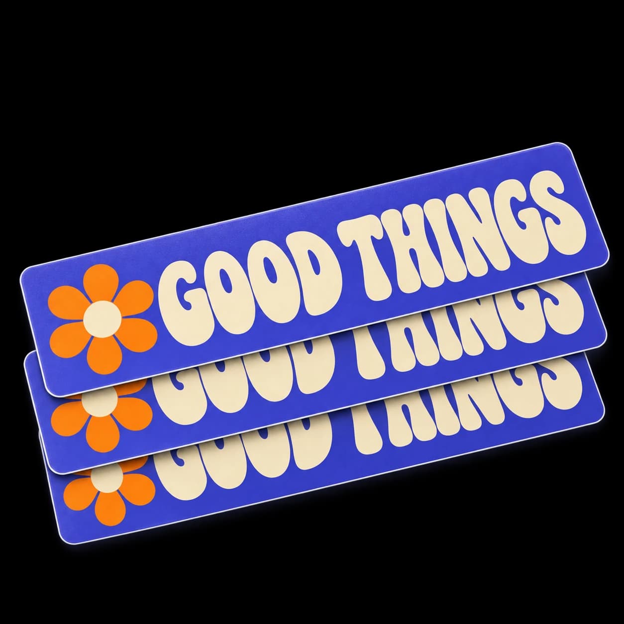 Stack of purple Good Things stickers with rounded corners, an orange flower, and cream lettering